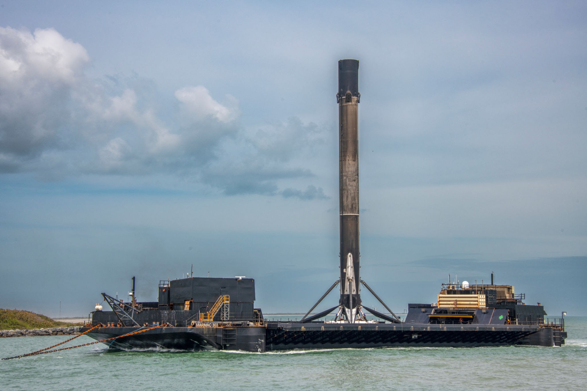 A recovered SpaceX Falcon 9 first-stage booster stands vertically on a drone ship in the middle of the ocean, a visual example of reusable rocket technology that reduces operational expenditure (OPEX) in quantitative models.